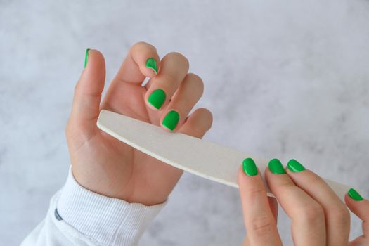 Manicured female hands with stylish green nails. Trendy modern design manicure. Gel nails. Skin care. Beauty treatment. Nail care. Wellness. Trendy colors. Manicure tools. Professional Hardware Manicure