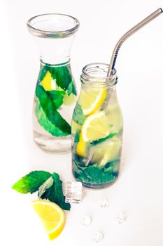 Mojito refreshing cocktail with eco metal drinking straw, alcohol drink. Lemonade with lemon and mint leaves on light background. Ice cubes. Summer refreshing detox drinks. Clean eating, healthy lifestyle concept, Diet. Nutrition.