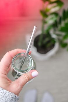 Top view female hand drinking water from eco bottle with metal reusable straw tube. Mindfulness meditation. The concept of healthy nutrition, environmental friendliness and zero waste. Self-isolation is beneficial