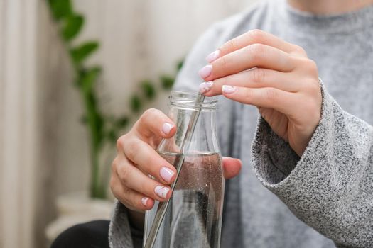 Young millennial blonde woman drinking water from eco bottle with metal reusable straw tube and doing yoga exercise stretching fitness at balcony home. Mindfulness meditation. The concept of healthy nutrition, environmental friendliness and zero waste. Self-isolation is beneficial