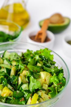 Salad of fresh green vegetables and herbs. Cooking healthy diet or vegetarian food. Step by step recipe. Healthy eating. Ingredients for salad. Raw food concept. A variety of organic fruits and vegetables with avocado. Vegan menu. Fresh spinach and green onion leaves, arugula. Flax seeds