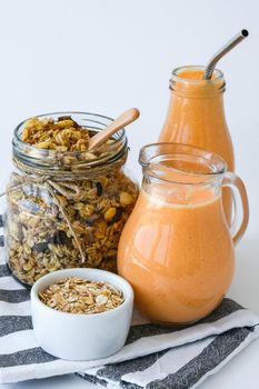 Seasonal pumpkin carrot smoothie drink detox with eco metal drinking straw Glass jar granola muesli oatmeal breakfast. Orange smoothie. Clean eating, weight loss, healthy dieting food concept Fruit vegetable drink fitness