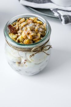 Healthy breakfast. Oatmeal Granola with greek yogurt and nuts banana muesli in jars on light background. Vegan, vegetarian and weight loss diet concept. Detox menu. Healthy eating food