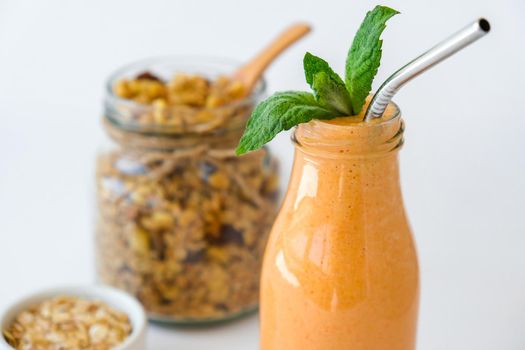 Seasonal pumpkin carrot smoothie drink detox with eco metal drinking straw Glass jar granola muesli oatmeal breakfast. Orange smoothie. Clean eating, weight loss, healthy dieting food concept Fruit vegetable drink fitness