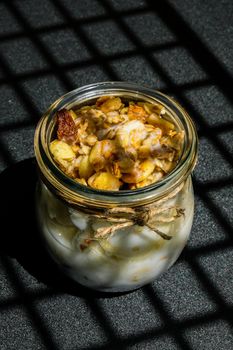 Healthy breakfast. Oatmeal Granola with greek yogurt and nuts banana muesli in jars on dark background. Trendy shadows Vegan, vegetarian and weight loss diet concept. Detox menu. Healthy eating food