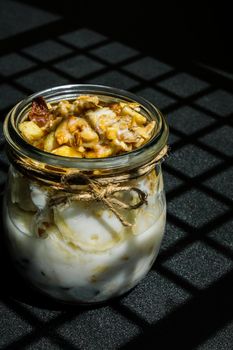 Healthy breakfast. Oatmeal Granola with greek yogurt and nuts banana muesli in jars on dark background. Trendy shadows Vegan, vegetarian and weight loss diet concept. Detox menu. Healthy eating food