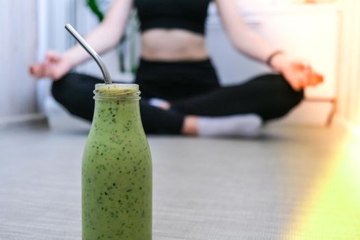 Seasonal Matcha green vegan smoothie with chia seeds and mint smoothie drink detox. Woman doing yoga on background Clean eating, weight loss, healthy dieting food concept. Fitness training workout at home.