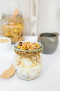 Healthy breakfast. Oatmeal Granola with greek yogurt and nuts banana muesli in jars on light background. Vegan, vegetarian and weight loss diet concept. Detox menu. Healthy eating food