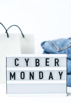 Light board with text CYBER MONDAY with paper shopping bags, jeans clothes. Big Sale online shopping concept. Promotion advertising. Holiday