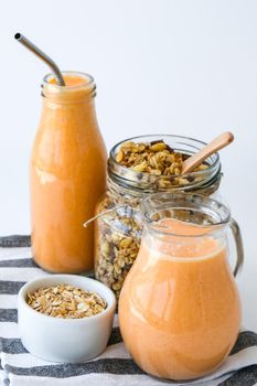 Seasonal pumpkin carrot smoothie drink detox with eco metal drinking straw Glass jar granola muesli oatmeal breakfast. Orange smoothie. Clean eating, weight loss, healthy dieting food concept Fruit vegetable drink fitness