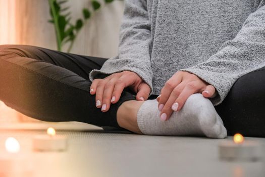 Close-up. Woman doing yoga exercise at home. Mindfulness meditation. Relax breathe easy pose gym healthy lifestyle concept. Burning candles light. Lotus asana. Atmosphere of relax and zen. Exercise to reach clarity of mind and perfect body. Padmasana