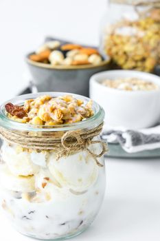 Healthy breakfast. Oatmeal Granola with greek yogurt and nuts banana muesli in jars on light background. Vegan, vegetarian and weight loss diet concept. Detox menu. Healthy eating food