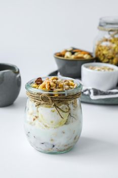 Healthy breakfast. Oatmeal Granola with greek yogurt and nuts banana muesli in jars on light background. Vegan, vegetarian and weight loss diet concept. Detox menu. Healthy eating food