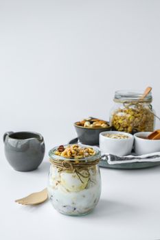 Healthy breakfast. Oatmeal Granola with greek yogurt and nuts banana muesli in jars on light background. Vegan, vegetarian and weight loss diet concept. Detox menu. Healthy eating food