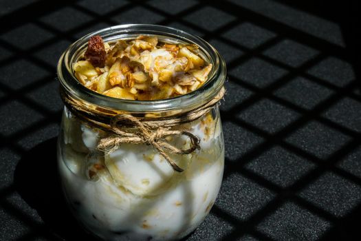 Healthy breakfast. Oatmeal Granola with greek yogurt and nuts banana muesli in jars on dark background. Trendy shadows Vegan, vegetarian and weight loss diet concept. Detox menu. Healthy eating food