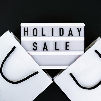 Light board with text HOLIDAY SALE with paper shopping bags. Big Sale online shopping concept. Promotion advertising. Holiday Cyber monday.