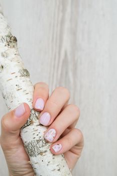 Closeup elegant pastel natural modern design manicure. Female hands holding Tree Trunk. Gel nails. Nude manicure. Beige color. Clean skin. Spa salon, advertisement. Skin care. Beauty. Nail care. Beauty treatment. Copy space