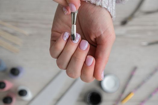 Modern female nude design manicure. Nail care, Self care. Do manicure by yourself while staying at home. Female hands and manicure tools. Spa salon. Professional Hardware Manicure. Procedure for the preparation of nails. Cuticle Pusher Remover. Nail file scissors