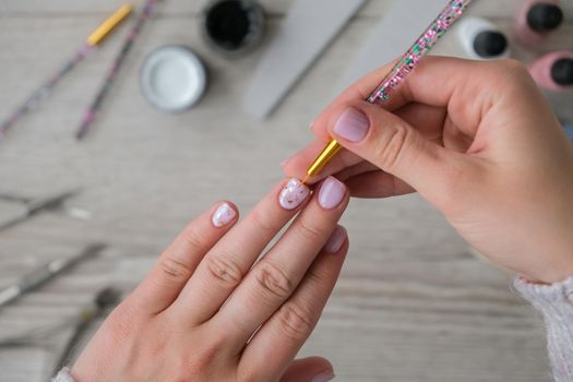Modern female nude design manicure. Nail care, Self care. Do manicure by yourself while staying at home. Female hands and manicure tools. Spa salon. Professional Hardware Manicure. Procedure for the preparation of nails. Cuticle Pusher Remover. Nail file scissors