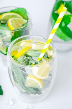 Mojito refreshing cocktail with eco paper drinking straw, alcohol drink. Lemonade with lemon and mint leaves on light background. Ice cubes. Summer refreshing detox drinks. Clean eating, healthy lifestyle concept, Diet. Nutrition.