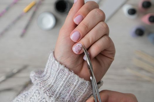 Modern female nude design manicure. Nail care, Self care. Do manicure by yourself while staying at home. Female hands and manicure tools. Spa salon. Professional Hardware Manicure. Procedure for the preparation of nails. Cuticle Pusher Remover. Nail file scissors