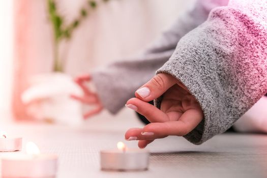 Close-up. Woman doing yoga exercise at home. Mindfulness meditation. Relax breathe easy pose gym healthy lifestyle concept. Burning candles light. Lotus asana. Atmosphere of relax and zen. Exercise to reach clarity of mind and perfect body. Padmasana