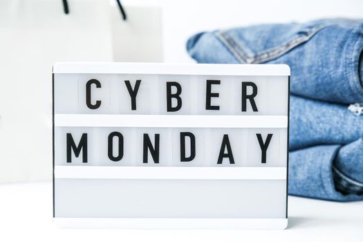 Light board with text CYBER MONDAY with paper shopping bags, jeans clothes. Big Sale online shopping concept. Promotion advertising. Holiday