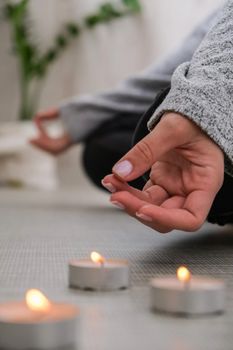 Close-up. Woman doing yoga exercise at home. Mindfulness meditation. Relax breathe easy pose gym healthy lifestyle concept. Burning candles light. Lotus asana. Atmosphere of relax and zen. Exercise to reach clarity of mind and perfect body. Padmasana