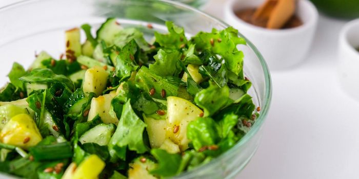 Salad of fresh green vegetables and herbs. Cooking healthy diet or vegetarian food. Step by step recipe. Healthy eating. Ingredients for salad. Raw food concept. A variety of organic fruits and vegetables with avocado. Vegan menu. Fresh spinach and green onion leaves, arugula. Flax seeds