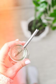 Top view female hand drinking water from eco bottle with metal reusable straw tube. Mindfulness meditation. The concept of healthy nutrition, environmental friendliness and zero waste. Self-isolation is beneficial