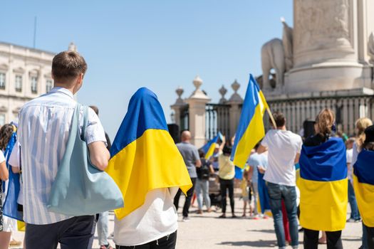 Portugal, Lisbon April 2022: The demonstration on Commerce Square in support of Ukraine and against the Russian aggression. Protesters against Russia's war Many people with Ukrainian flags. Crowd