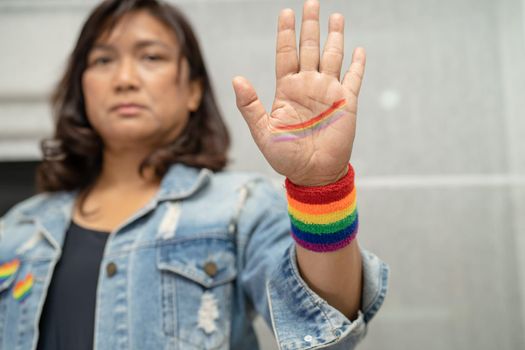 Asian lady wearing rainbow flag wristbands, symbol of LGBT pride month celebrate annual in June social of gay, lesbian, bisexual, transgender, human rights.