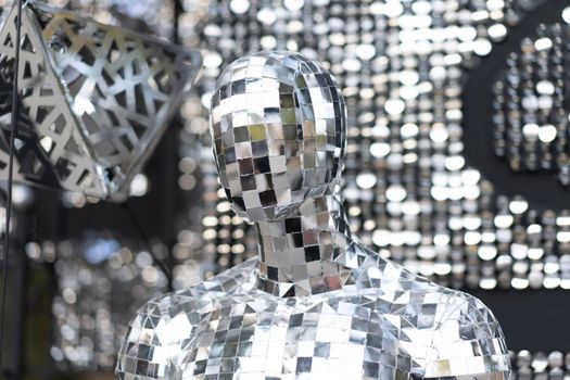 Male mannequin covered with slices of a mirror on a black background mr disco. a super cool disco club character against sparkling background