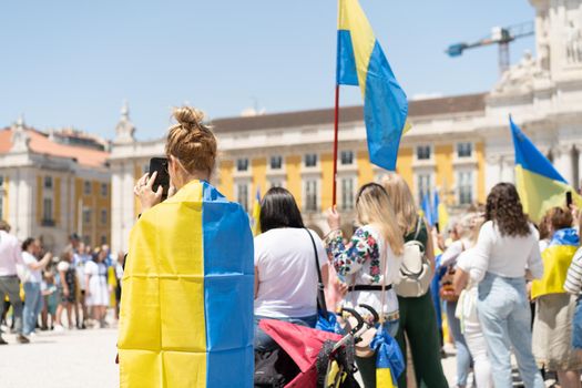 Portugal, Lisbon April 2022: The demonstration on Commerce Square in support of Ukraine and against the Russian aggression. Protesters against Russia's war Many people with Ukrainian flags. Crowd
