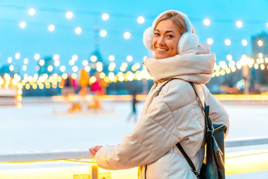 Woman winter Christmas mood Lovely middle-aged female warm winter jackets fur headphones stands ice rink background Town Square lifestyle Happy holiday woman walk snowy day Winter leisure