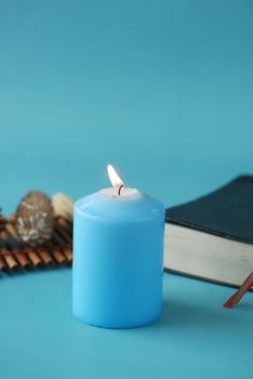 Natural candle in a glass jar and dried flowers on blue .