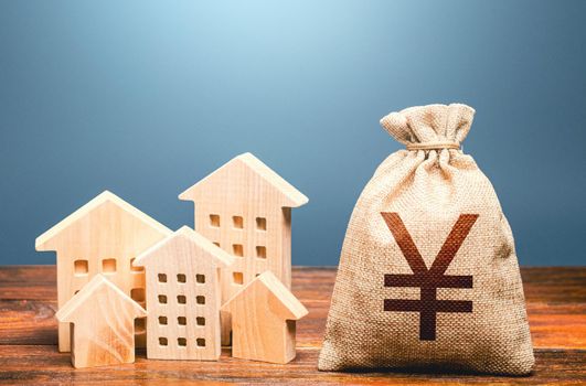 Houses and chinese yuan or japanese yen money bag. Energy efficiency and costs for heating and home services. Community municipal budget. Investments in real estate and construction industry.