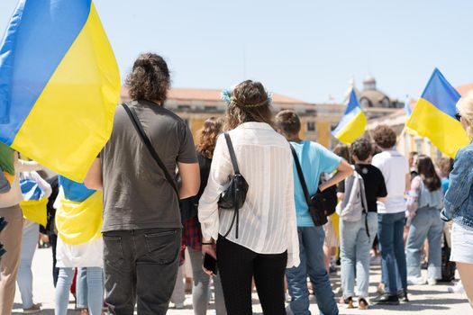 Portugal, Lisbon April 2022: The demonstration on Commerce Square in support of Ukraine and against the Russian aggression. Protesters against Russia's war Many people with Ukrainian flags. Crowd