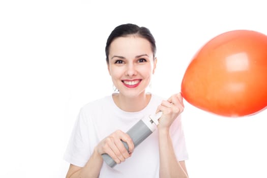 happy woman in white t-shirt inflates red balloon, white studio background. High quality photo