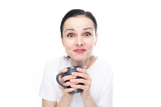 happy brunette woman in a white t-shirt holding a mug in her hands, white background. High quality photo