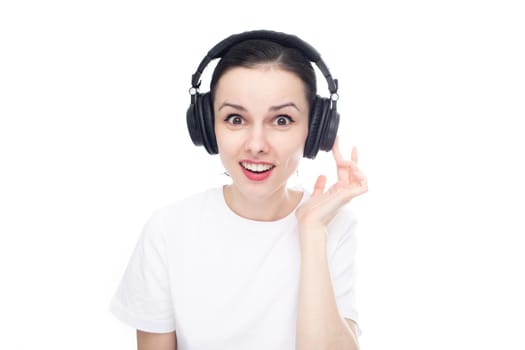 surprised brunette woman in big headphones listens to music, white background. High quality photo