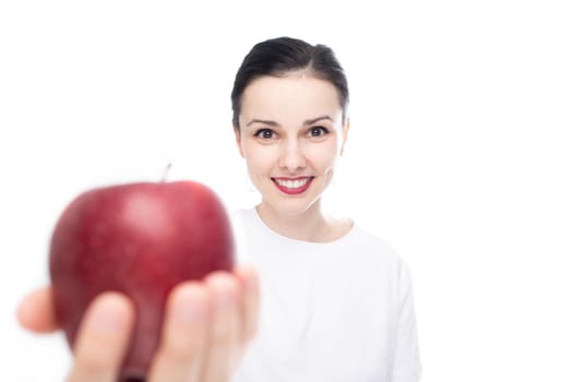 smiling woman in white t-shirt sharing red apple, white studio background. High quality photo
