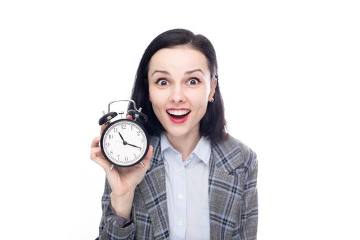 smiling woman manager in office suit holding alarm clock, white studio background. High quality photo