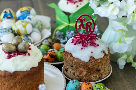close up topper Easter cakes with Russian letters XB means Christ is Risen. Happy easter concept. Easter wooden table with Easter cakes and colored eggs. soft focus