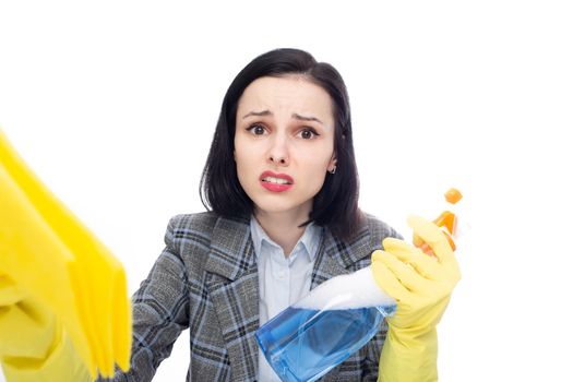 smiling businesswoman in office suit with cleaning gloves holding rags and household chemicals in her hands, white studio background. High quality photo