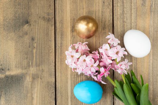 blue, white and golden eggs and pink hyacinth flowers on wooden table. Happy Easter concept. Easter background Top view
