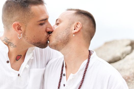 Close up portrait of an homosexual couple kissing tenderly on a topical beach