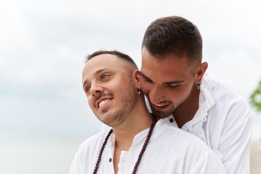 Close up photo of a gay couple in love embracing tenderly on a beach