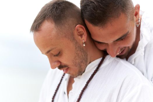 Portrait of two homosexual men in white clothes embracing with tender expression