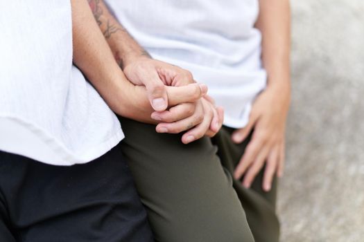 Close up view and cropped photo of two gay men holding a hand next to a rocky formation outdoors